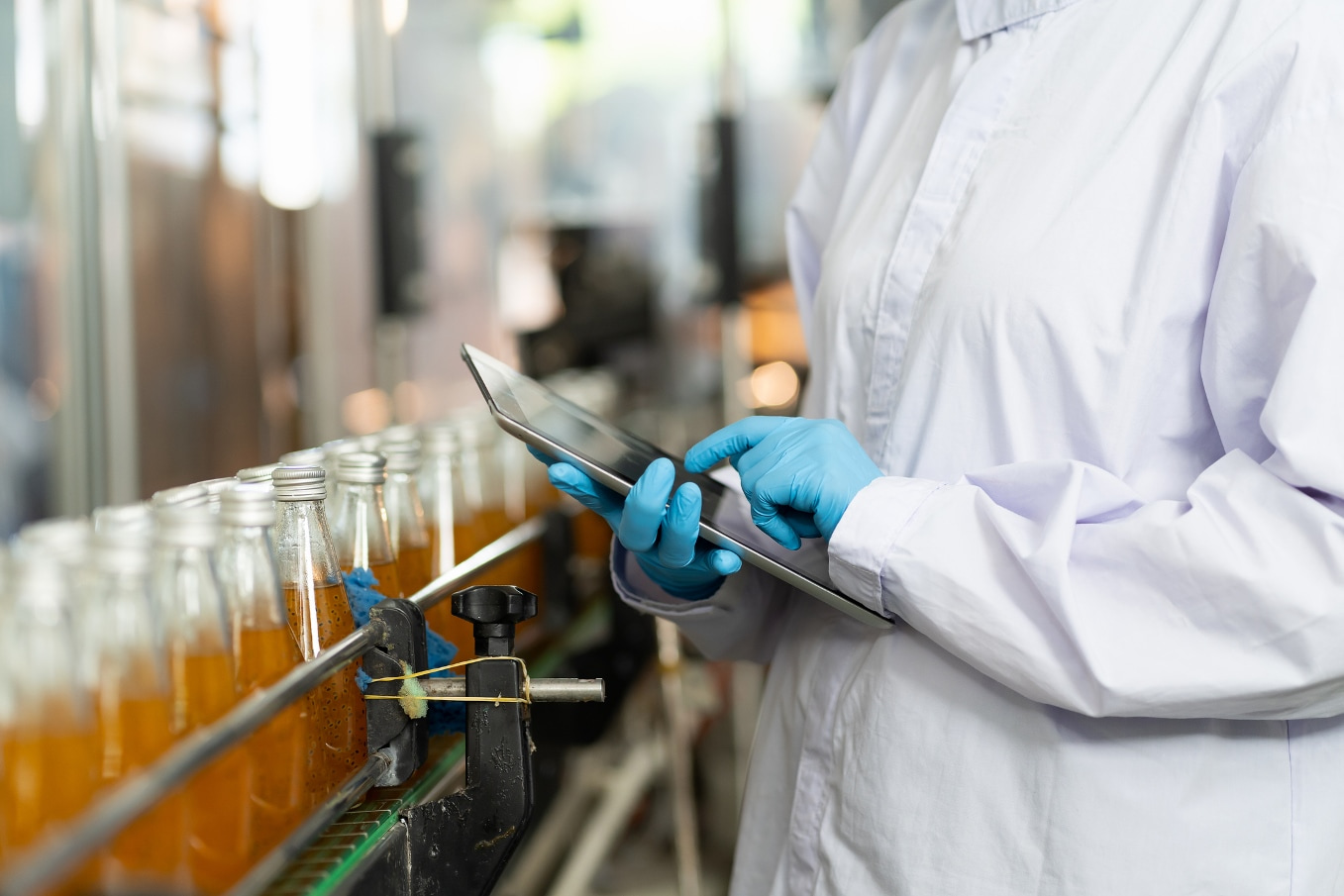 Quality control worker reviews tablet computer in a beverage manufacturing facility.